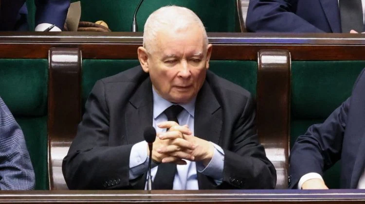 Jarosław Kaczyński ukarany naganą przez komisję etyki poselskiej Starszy mężczyzna o siwych włosach siedzi w ławach sejmowych, ubrany w ciemny garnitur i białą koszulę, z dłońmi splecionymi przed sobą, w tle widać innych siedzących polityków.