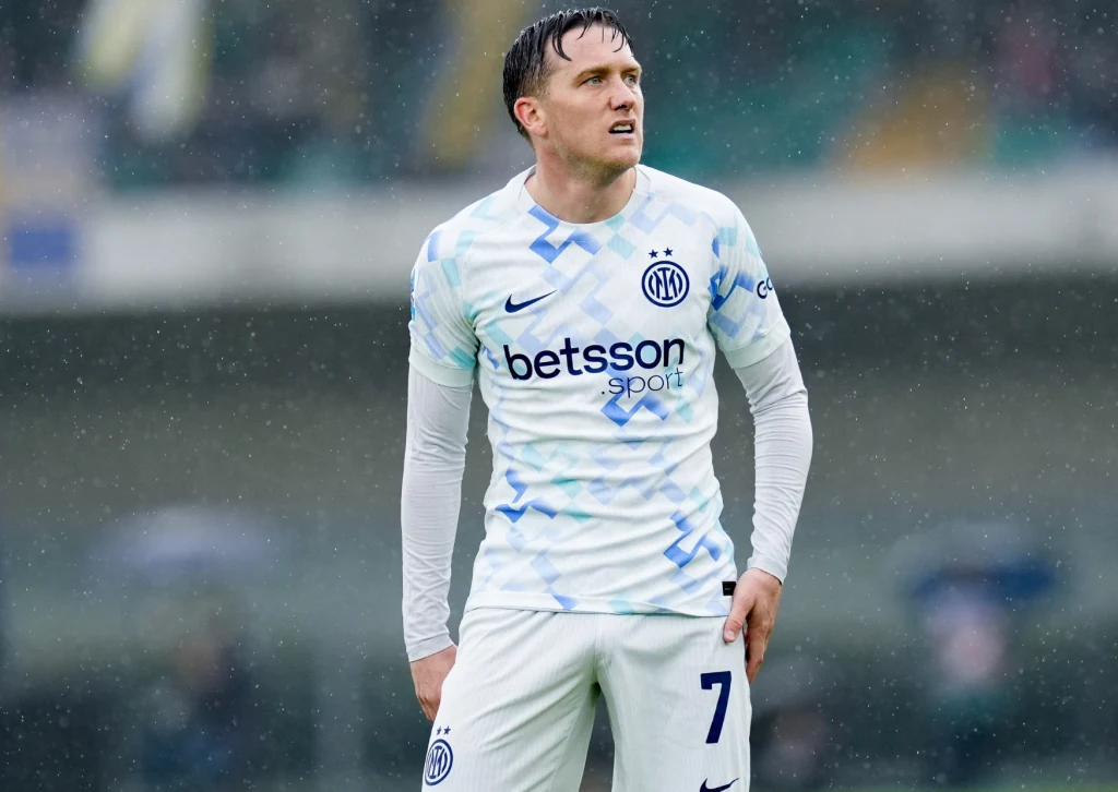 Piotr Zieliński Piłkarz w jasnym stroju z numerem 7 i logo klubu Inter Mediolan stoi na boisku podczas meczu rozegranego w deszczowych warunkach, wyrażając skupienie.