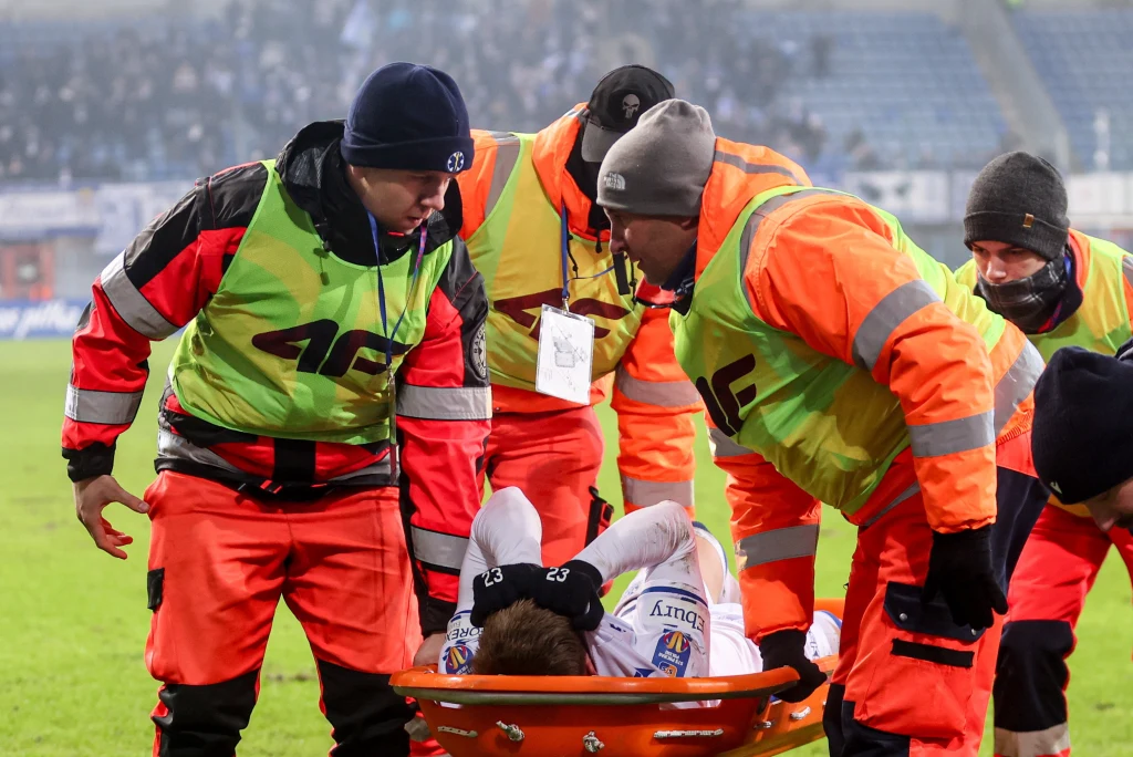 Mecz z Piastem Gliwice zakończył się dla Gisliego Thordarsona bolesną kontuzją Ratownicy medyczni w odblaskowych kamizelkach udzielają pomocy kontuzjowanemu piłkarzowi podczas meczu, przenosząc go na noszach po boisku stadionu.