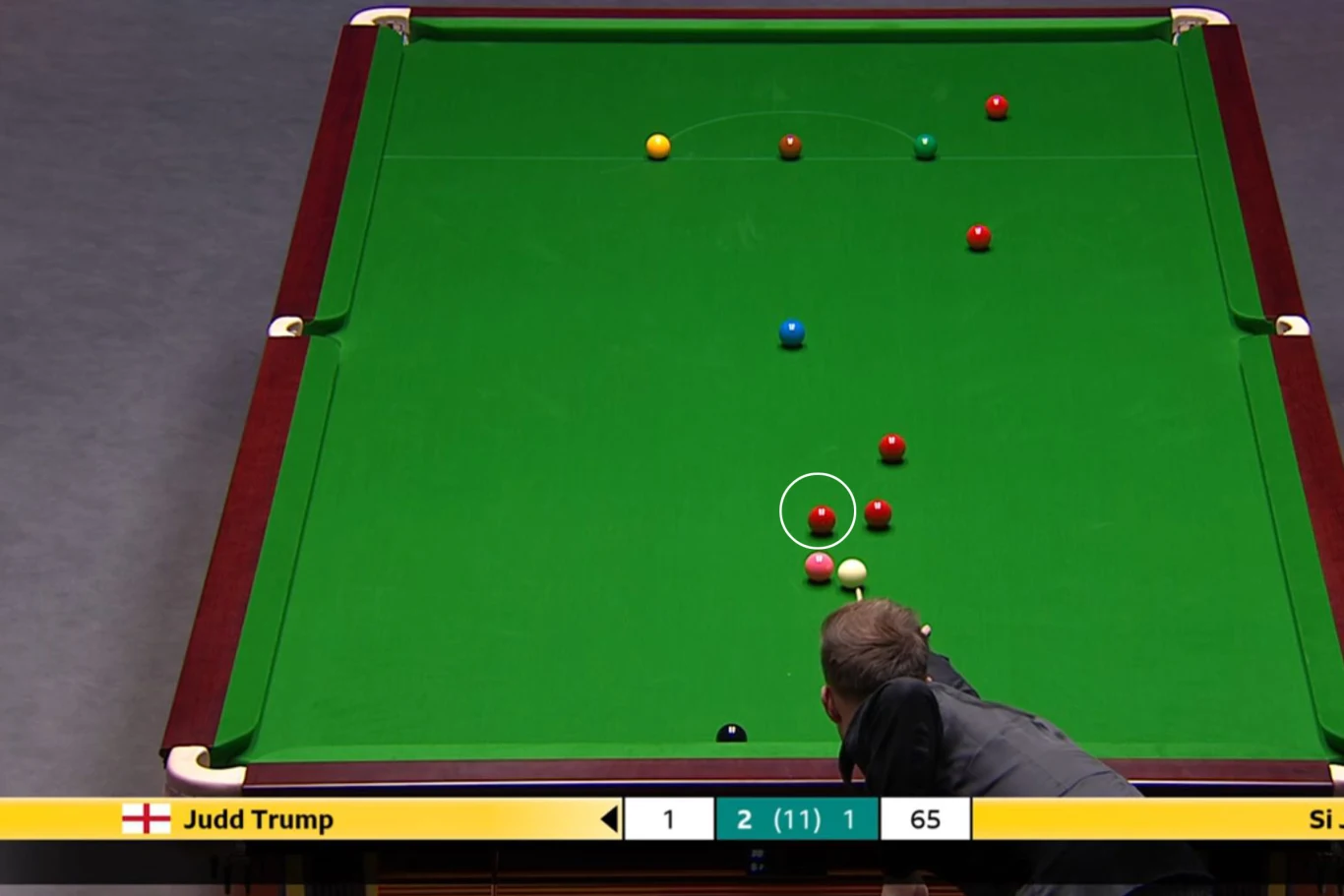 Stół bilardowy z kulami snookerowymi, zawodnik w trakcie rozgrywki przygotowuje się do strzału. W dolnej części ekranu widoczne informacje o rozgrywce i zawodnikach.