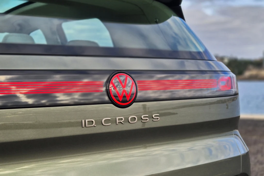 Tylna część samochodu Volkswagen z widocznym logo marki oraz oznaczeniem modelu ID. Cross, z nowoczesnym wzornictwem i światłami LED, na tle rozmytego krajobrazu.