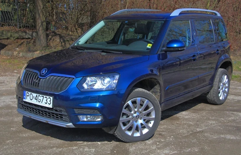 Silnik 1.2 TSI montowano m.in. w Skodach Yeti Niebieski SUV marki Škoda zaparkowany na pustym placu, widoczny z przodu i z boku. Samochód jest czysty, z wyraźnie widoczną rejestracją i dobrze utrzymaną karoserią. W tle widoczne są drzewa oraz ogrodzenie.