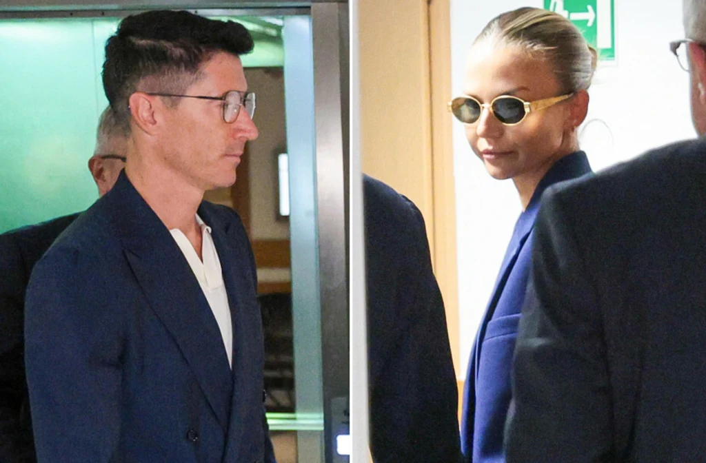 Para ubrana w eleganckie, ciemne marynarki, kobieta w okularach przeciwsłonecznych, oboje znajdują się w jasnym wnętrzu w towarzystwie kilku innych osób.