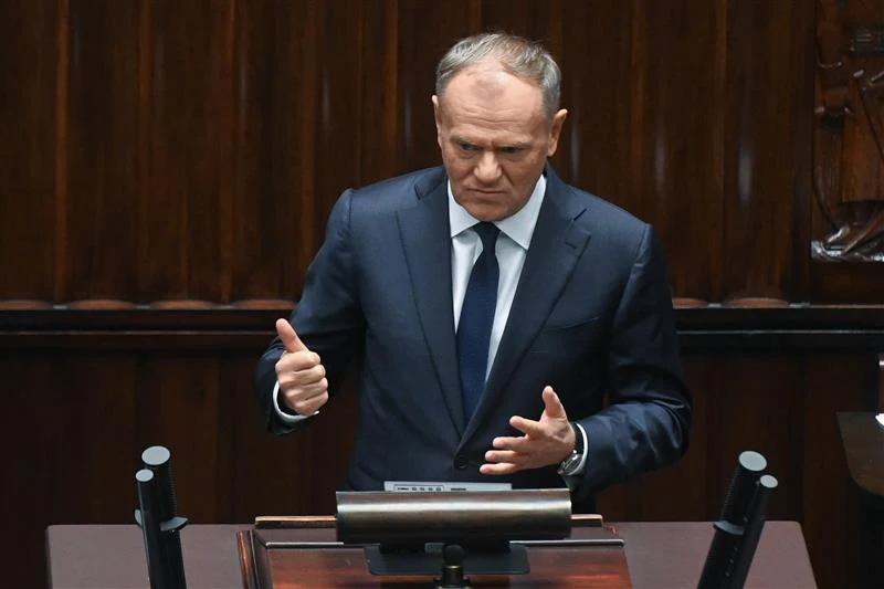 Mężczyzna w garniturze przemawia zza mównicy w sali sejmowej, gestykulując rękami i prezentując poważny wyraz twarzy.