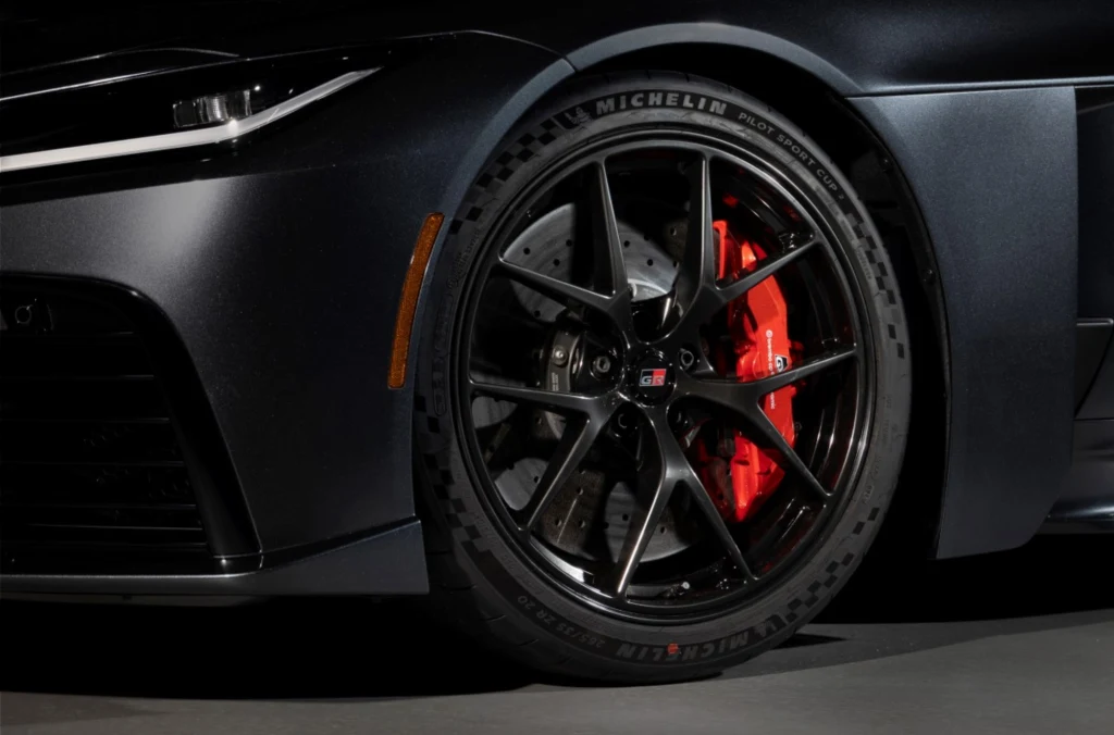 Toyota odwróciła klasyczny proces projektowania samochodu sportowego. Czarny aluminiowy felga samochodowa z widocznym czerwonym zaciskiem hamulcowym i oznaczeniem Michelin na oponie, fragment przedniej części sportowego auta.
