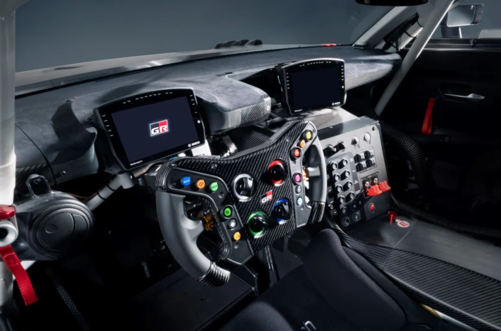Wskaźniki zaprojektowano tak, aby były czytelne także podczas jazdy torowej, gdzie margines błędu praktycznie nie istnieje. Kokpit samochodu wyścigowego z zaawansowaną kierownicą wielofunkcyjną, dwoma cyfrowymi wyświetlaczami oraz rozbudowanym panelem kontrolnym wyposażonym w liczne przyciski i przełączniki.