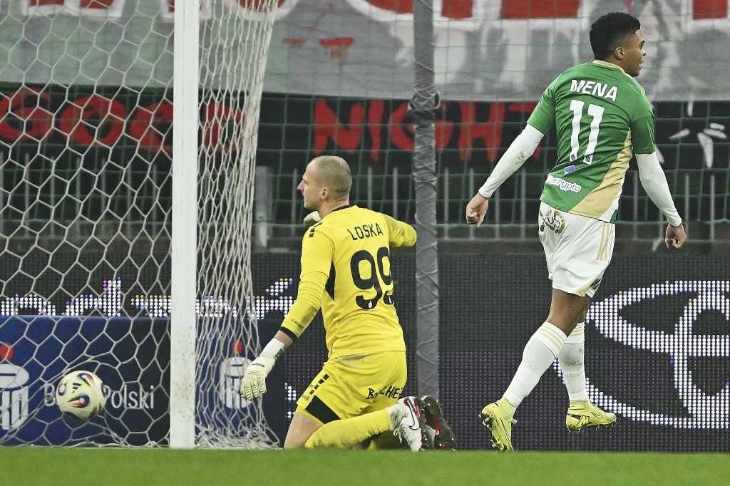 Dla bramkarza zabrzan Tomasza Loski starcie z Lechią okazało się koszmarem Piłkarz w zielono-białej koszulce z numerem 11 unosi ręce po zdobyciu gola, bramkarz w żółtym stroju z numerem 99 klęczy przy siatce, piłka znajduje się już w bramce, w tle widoczne fragmenty trybun oraz reklamy.