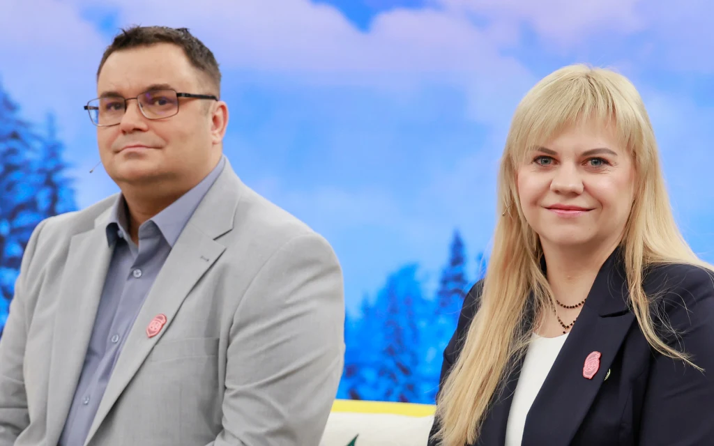 Mężczyzna w garniturze i okularach, kobieta w ciemnej marynarce, siedzą w studiu telewizyjnym