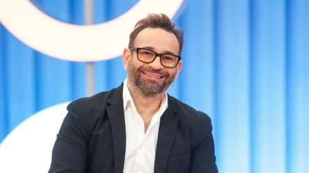 Stylista fryzur Maciej Maniewski w białej koszuli i czarnej marynarce, uśmiechnięty