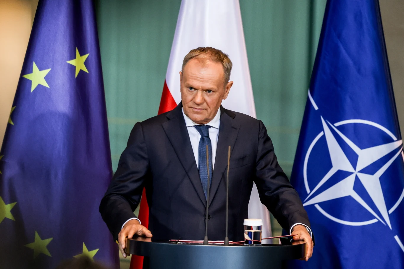 Nowa Strategia Bezpieczeństwa USA. Donald Tusk komentuje dokument, zwrócił się do Amerykanów Mężczyzna w garniturze przemawia przy mównicy, w tle widoczne są flagi Unii Europejskiej, Polski i NATO.