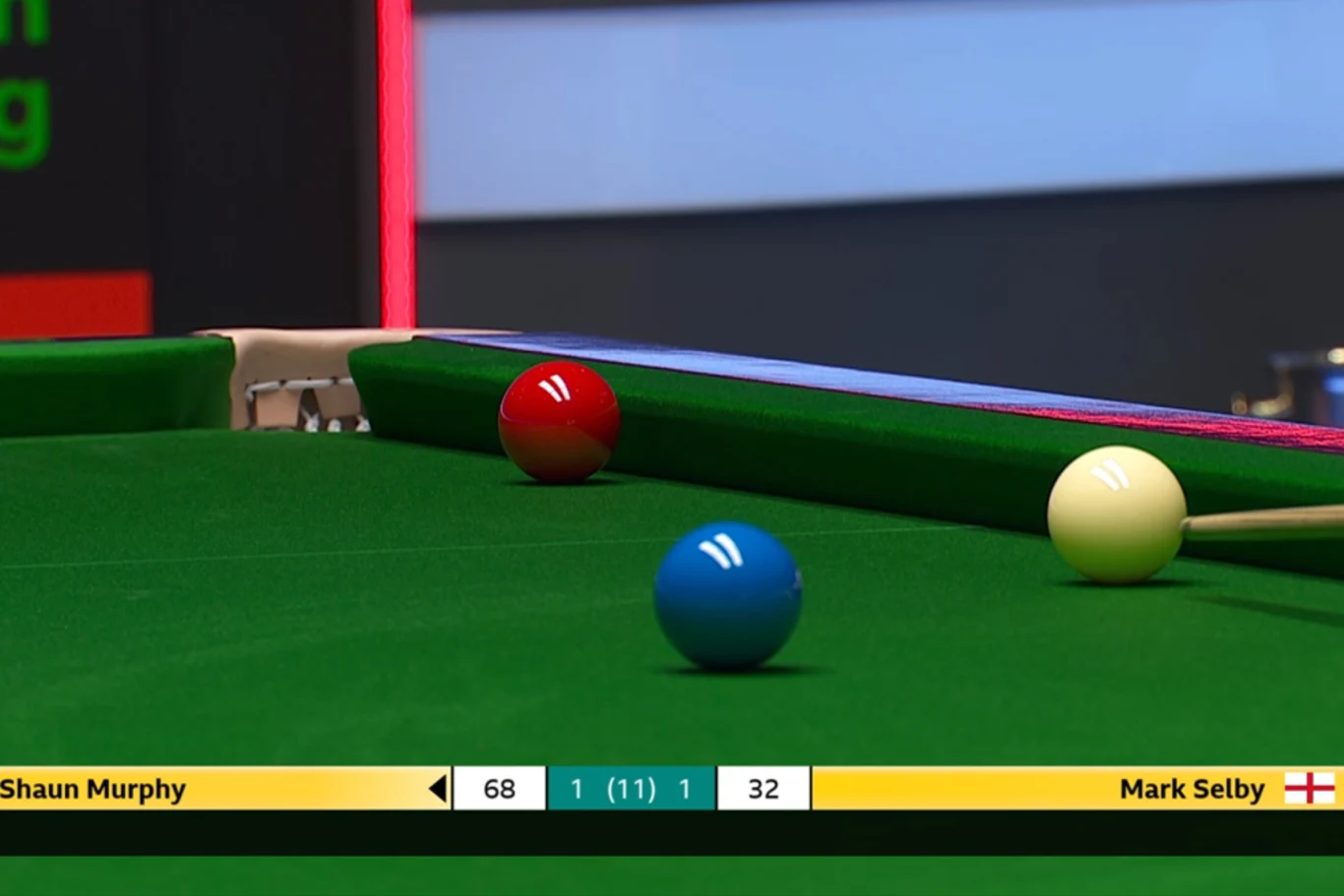Stół bilardowy z bilem żółtym, niebieskim i czerwonym blisko bandy. Na dolnej części ekranu wynik meczu pomiędzy Shaunem Murphy a Markiem Selbym.