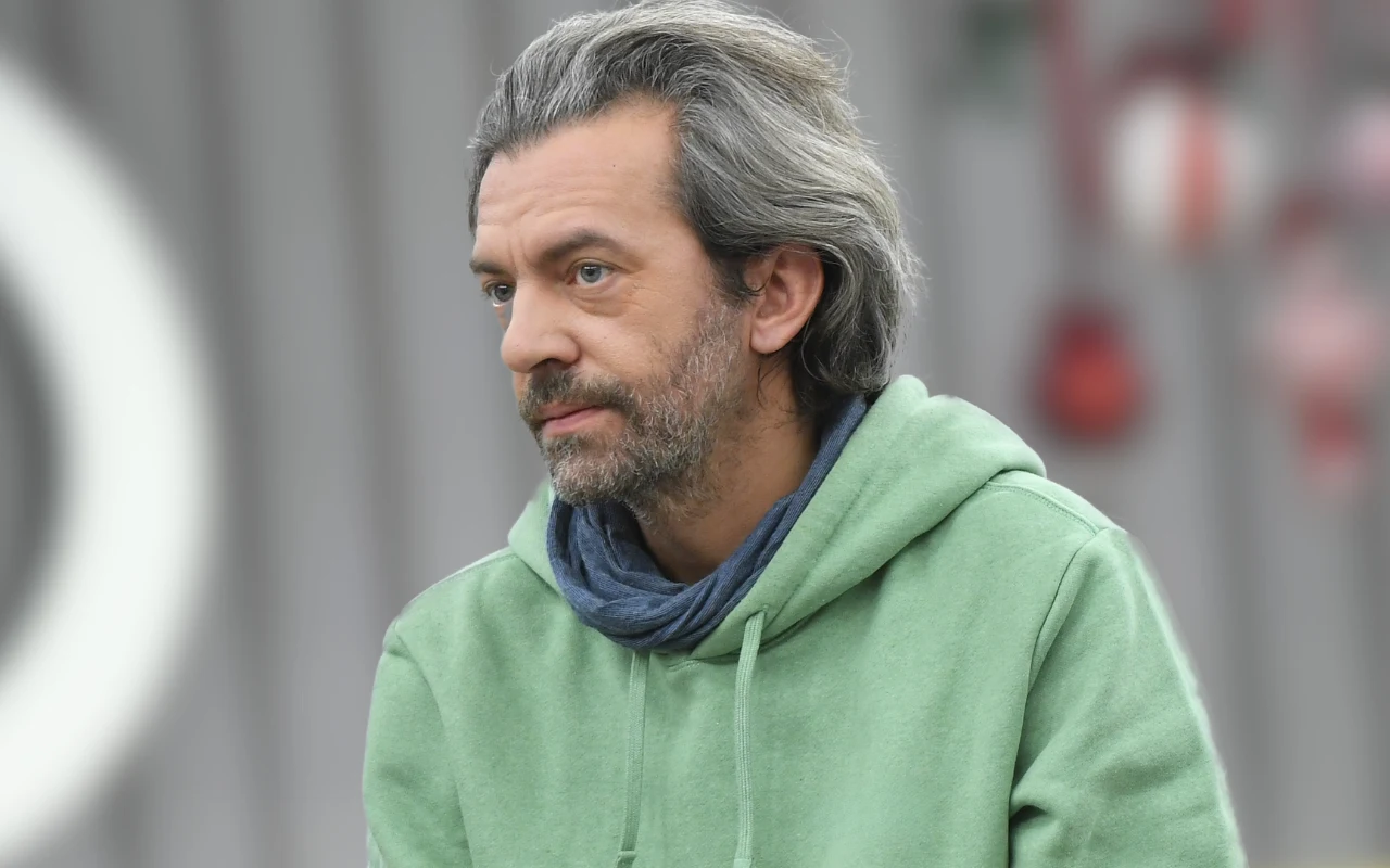 Dojrzały mężczyzna z siwymi włosami w jasnej bluzie z kapturem