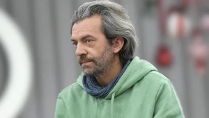 Dojrzały mężczyzna z siwymi włosami w jasnej bluzie z kapturem