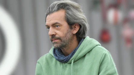 Dojrzały mężczyzna z siwymi włosami w jasnej bluzie z kapturem