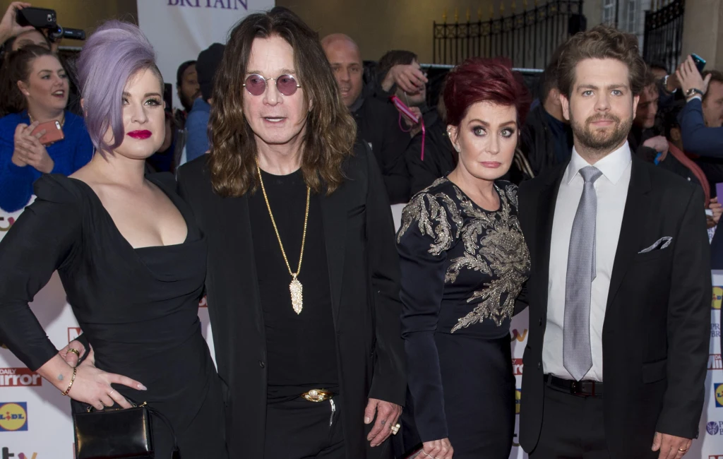 Ozzy Osbourne i jego najbliżsi: żona Sharon, córka Kelly i syn Jack - Londyn, 28 września 2015 r. Cztery osoby pozują razem do zdjęcia na czerwonym dywanie podczas oficjalnej gali. Kobieta po lewej ma fioletowe włosy upięte na bok i czarną, wieczorową suknię. Obok niej stoi mężczyzna z długimi włosami, ubrany na czarno i noszący okulary przeciwsłon...