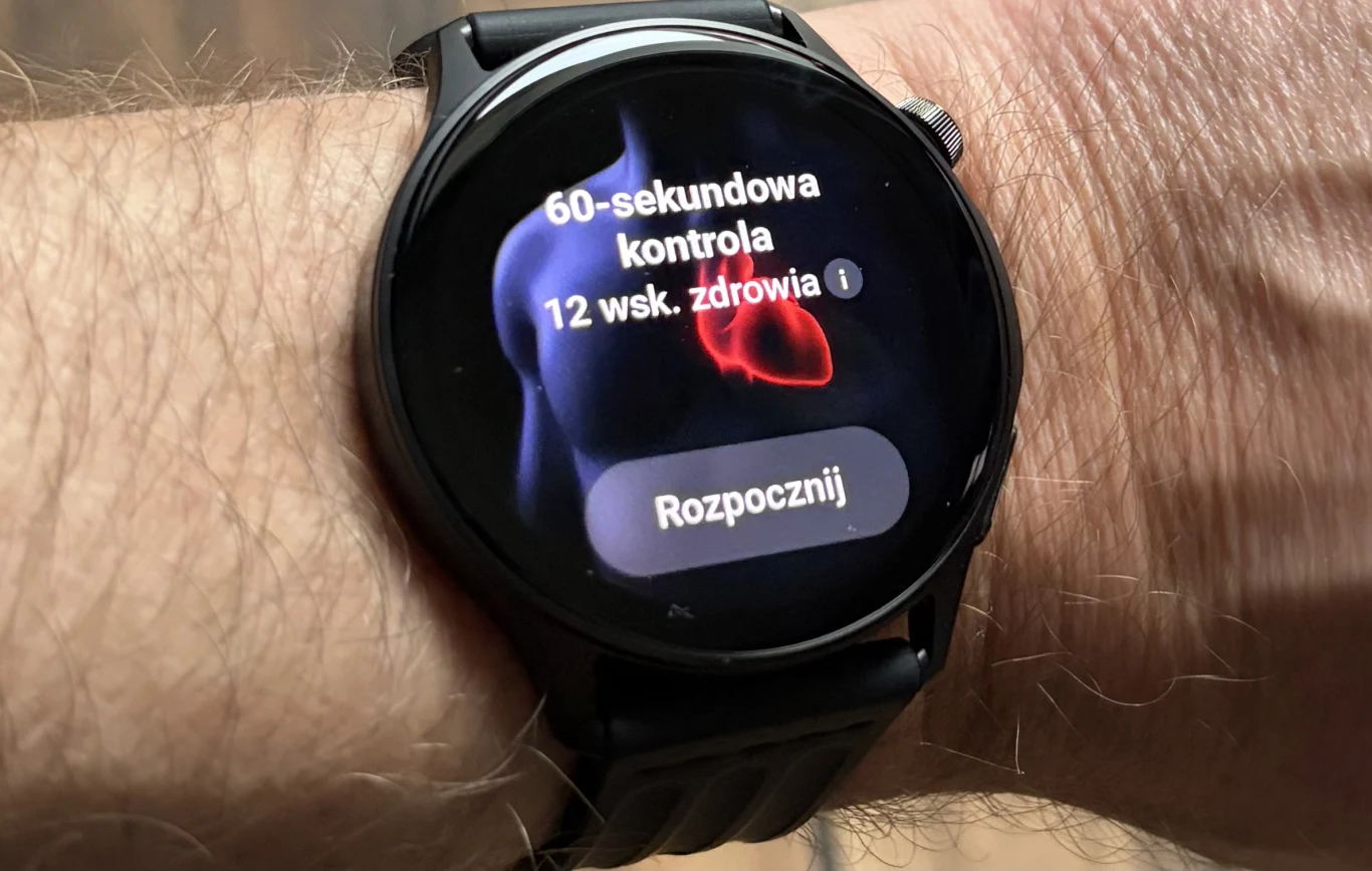 Funkcja 60-sekundowa kontrola pozwala uzyskać informacje o zdrowiu. Smartwatch na nadgarstku z widocznym ekranem wyświetlającym opcję uruchomienia 60-sekundowej kontroli zdrowia oraz wizualizacją serca w tle.