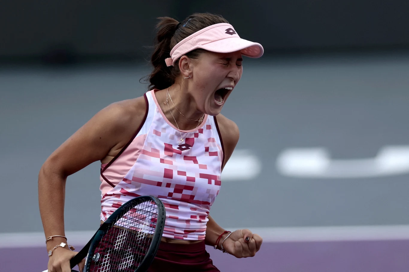 Kamilla Rachimowa porzuciła Rosję i może świętować zdobycie tytułu w nowych barwach Tenisistka krzycząca z emocji po wykonaniu udanego zagrania, trzymająca rakietę tenisową, ubrana w sportowy top i czapeczkę, dynamiczna poza na tle kortu tenisowego.