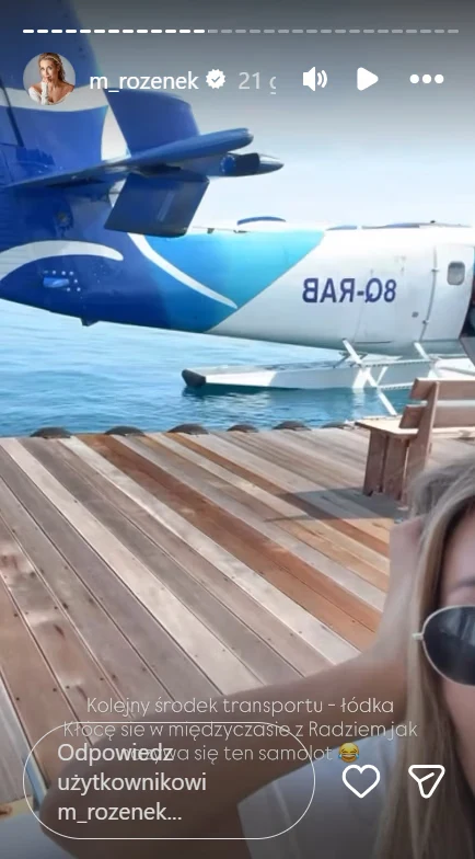 Małgorzata Rozenek-Majdan na wakacjach na Malediwach Fragment pokładu drewnianego pomostu nad wodą, część osoby w okularach przeciwsłonecznych oraz widoczny ogon i skrzydło niebiesko-białego samolotu wodnego.