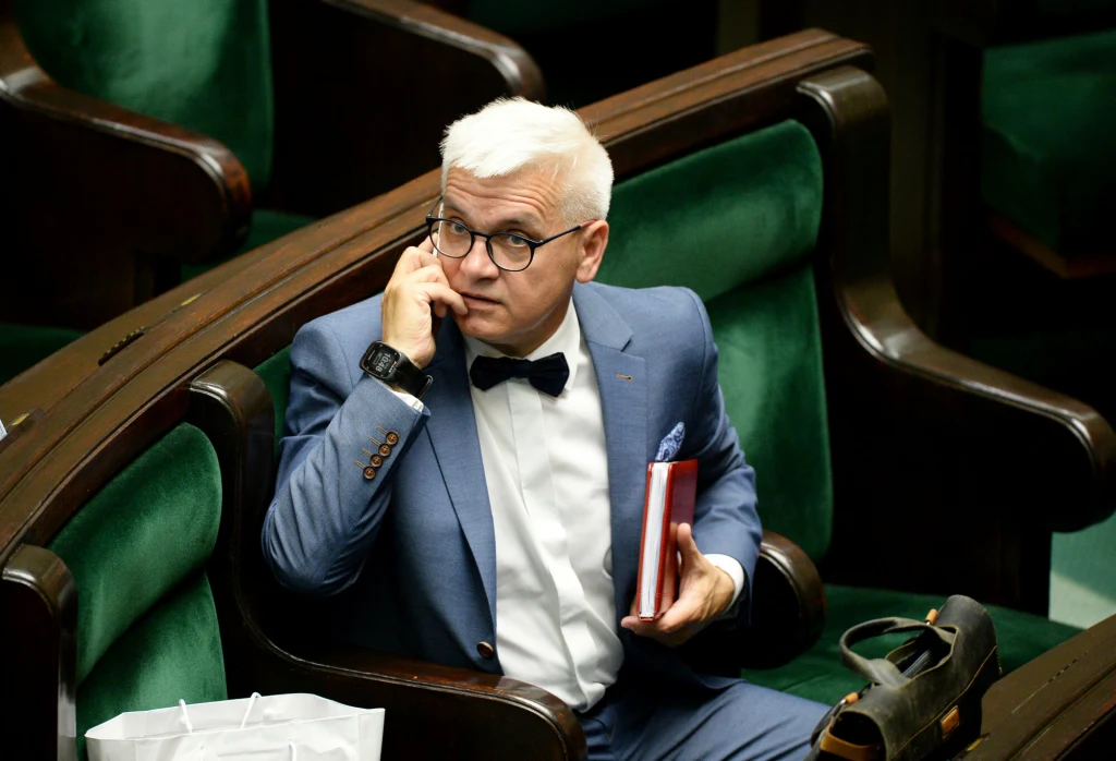RPP nie powiedziała ostatniego słowa? Wnorowski: Nie wykluczam kroku wstecz Mężczyzna w garniturze i muszce siedzi na zielonym fotelu, rozmawia przez telefon i trzyma w ręku czerwoną książkę. W tle widoczne są kolejne miejsca sali przypominającej salę obrad.