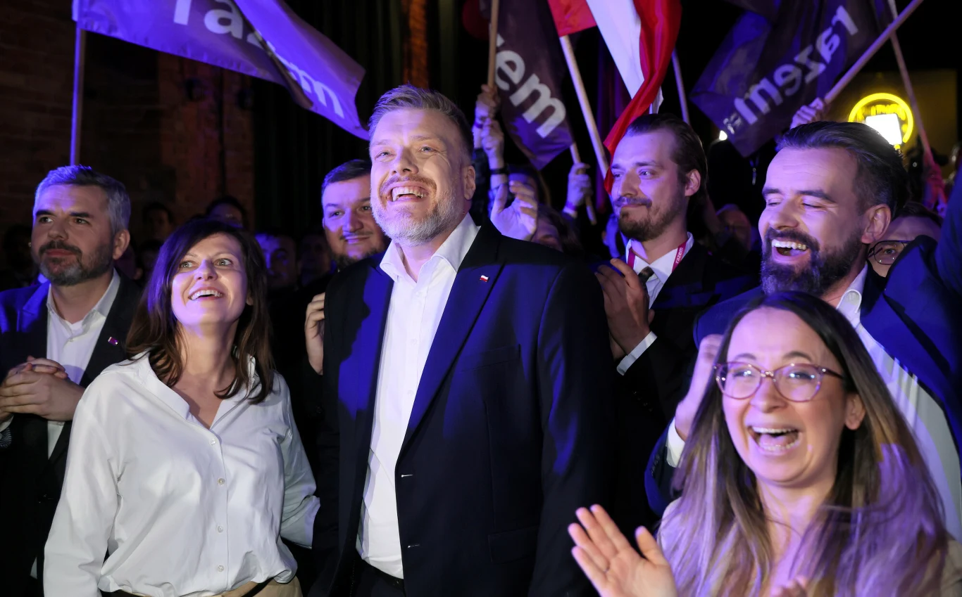 Po kampanii prezydenckiej Razem rośnie w siłę Grupa dorosłych osób, elegancko ubranych, stoi blisko siebie i wyraża radość w tłumie podczas wydarzenia politycznego. W tle widoczne flagi i transparenty z logo partii oraz żywiołowa atmosfera wieczornego zgromadzenia.