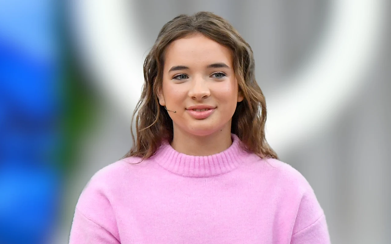 Magdalena Dudek w rozpuszczonych włosach i różowym świetle, lekko uśmiechnięta