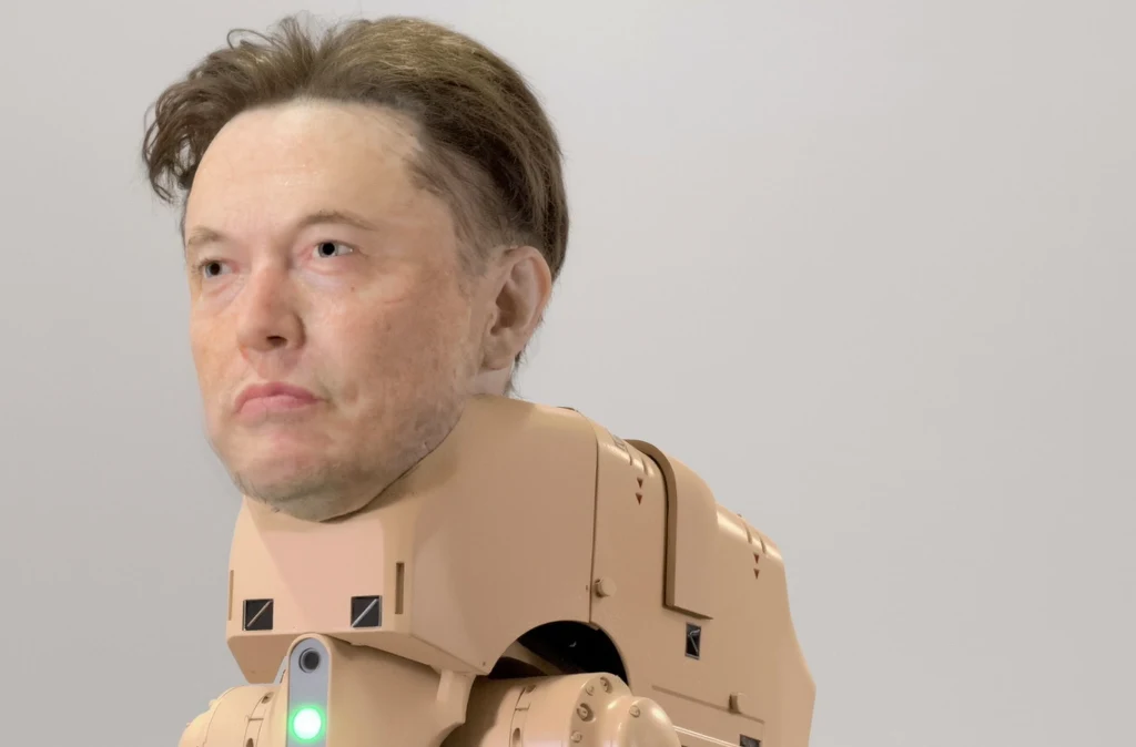 Robo-pies z maską Elona Muska na wystawie Beeple'a Głowa mężczyzny została cyfrowo umieszczona na ciele robota w kolorze beżowym z widocznym delikatnym zielonym światłem na klatce piersiowej, tło jest jednolite i jasne.