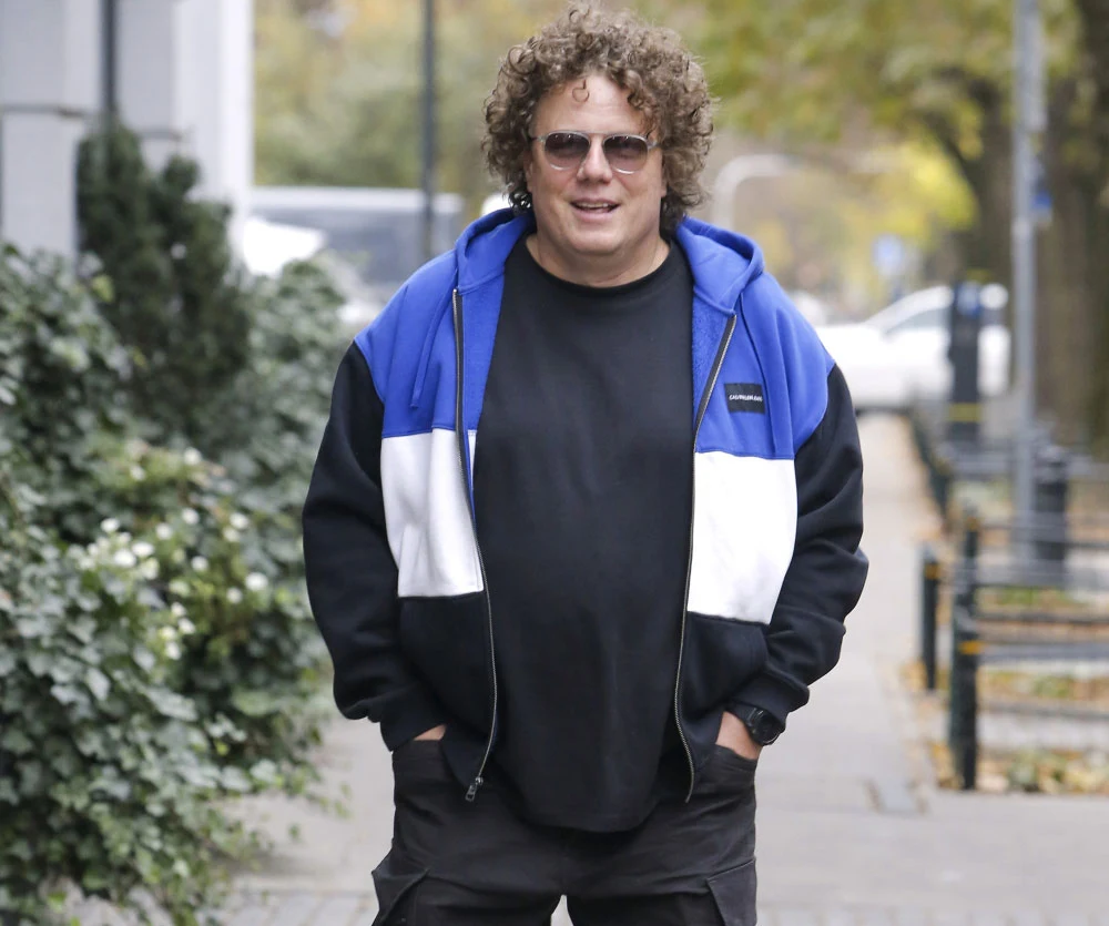 Sidney Polak od 1990 r. był perkusistą grupy T.Love Mężczyzna z kręconymi włosami w okularach przeciwsłonecznych, ubrany w sportową bluzę z niebieskimi, białymi i czarnymi elementami, stoi na chodniku w otoczeniu zieleni miejskiej.