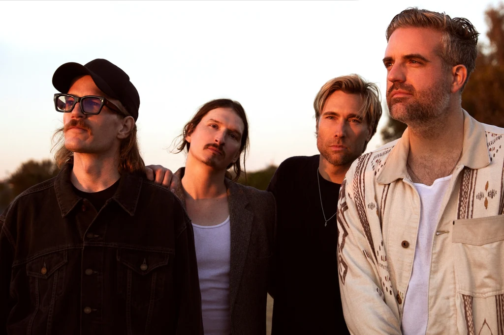 Zespół Kensington wydał nowy album "First Rodeo" Czterech mężczyzn stoi obok siebie na zewnątrz podczas zachodu słońca, przyjmując zamyślone pozy. Jeden z nich nosi okulary i czapkę, pozostali ubrani są w casualowe stroje, w tle widoczne rozmyte drzewa.