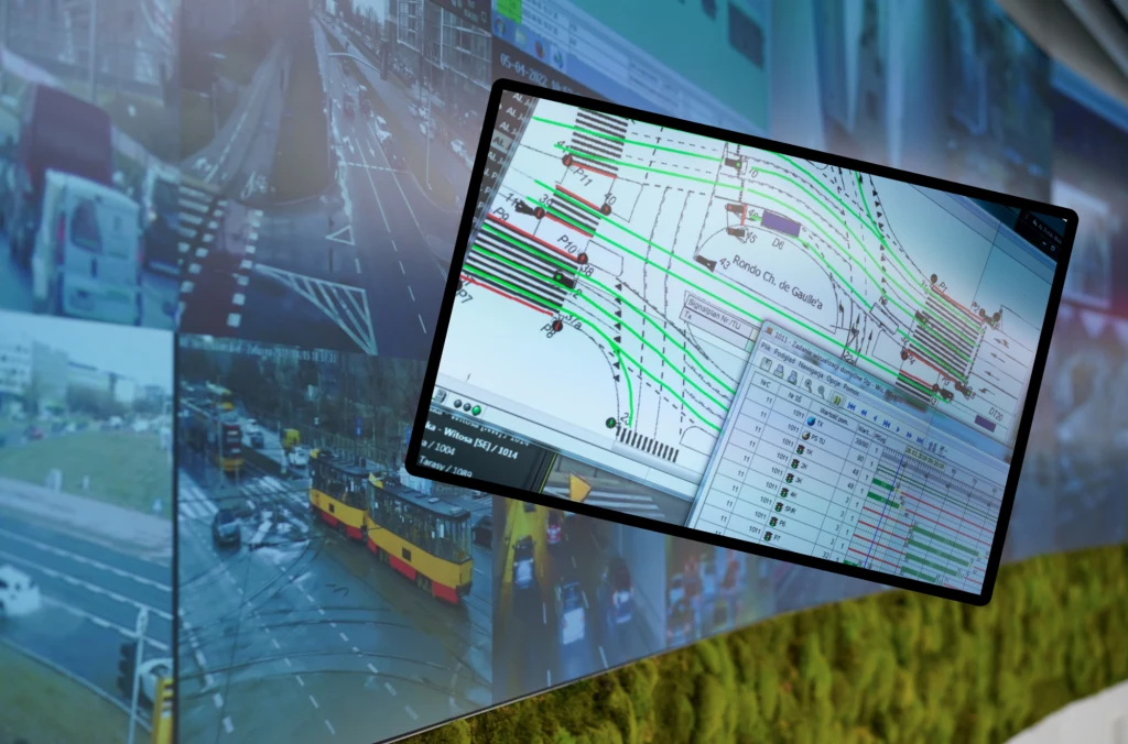 Tysiące kamer śledzą kierowców w Warszawie. To poprawi bezpieczeństwo. Ekran z podglądem kamer monitoringu miejskiego nadzoruje ruch samochodowy na skrzyżowaniu, nałożony schemat przedstawia plan sterowania ruchem oraz sygnalizację świetlną, widoczne są tramwaje i pojazdy na ulicach.