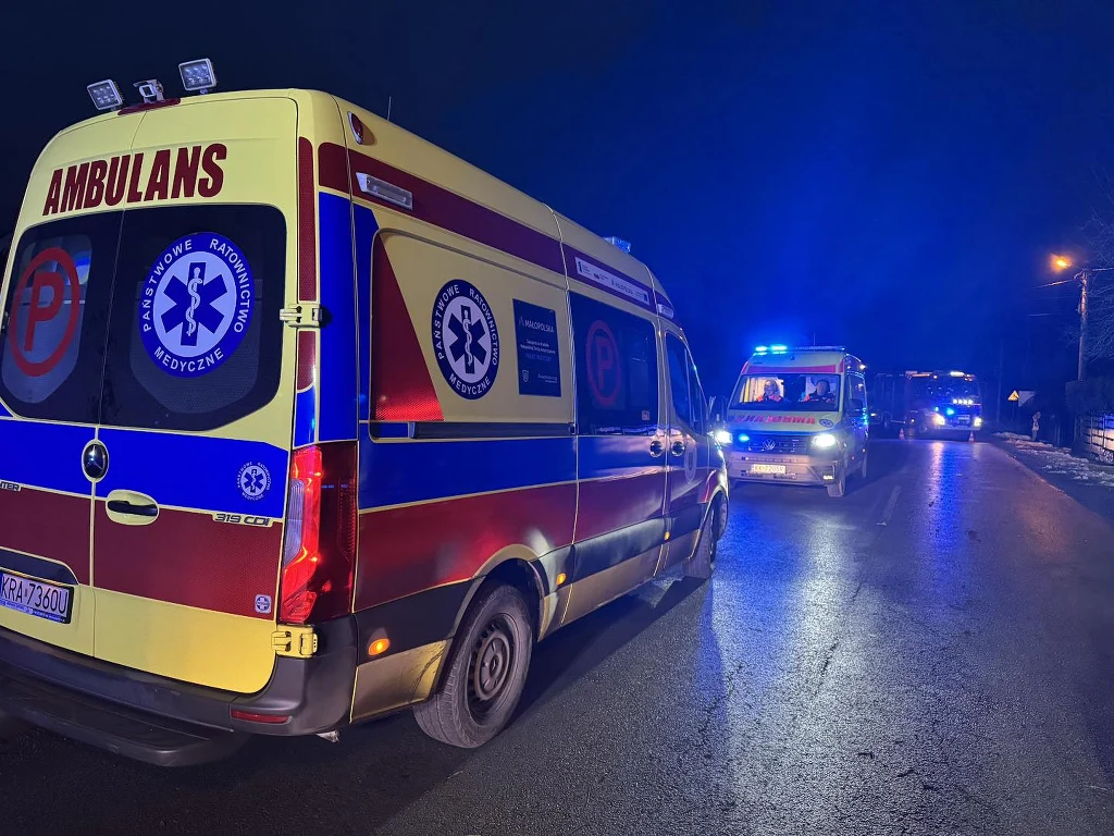 W wypadku zginął 21-letni mężczyzna Karetka pogotowia oraz inne pojazdy ratunkowe z włączonymi światłami sygnalizacyjnymi stoją na oświetlonej ulicy nocą.