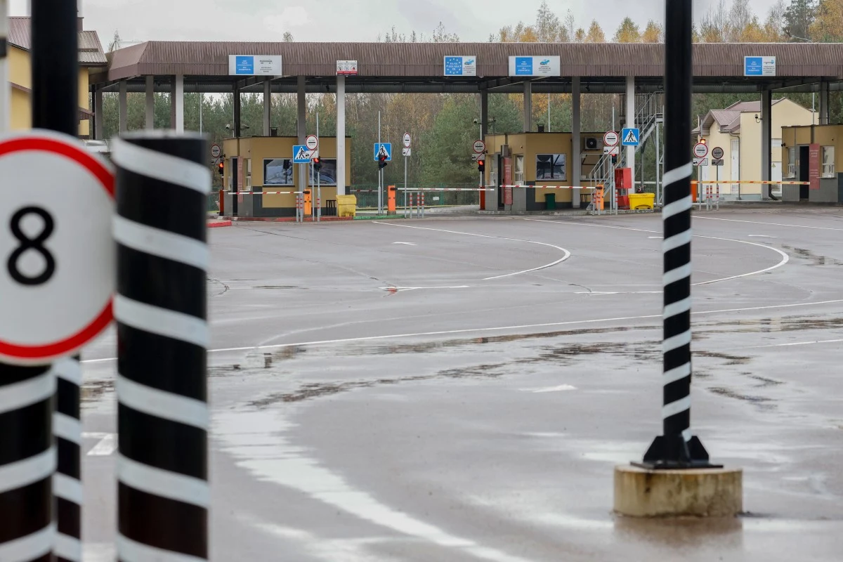 Granica litewsko-białoruska. Rząd w Wilnie wprowadził stan wyjątkowy Pusty przejazd przez przejście graniczne, budki kontrolne i barierki, oznakowanie drogowe oraz słupki graniczne, otoczenie pozbawione ruchu pojazdów i ludzi, w tle widoczne drzewa.