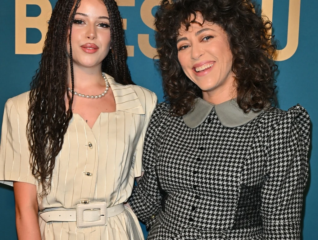 Anna Dąbrówka z Natalią Kukulską Dwie kobiety stoją obok siebie, uśmiechają się i patrzą w stronę obiektywu. Kobieta po lewej ma długie, zaplecione warkoczyki, jasną sukienkę z paskiem w talii oraz naszyjnik z pereł. Kobieta po prawej ma ciemne, kręcone włosy oraz ubrana jest w sukien...