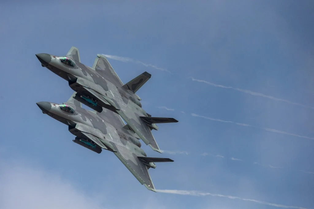 Korea Południowa poderwała myśliwce (zdj. ilustracyjne) Dwa wojskowe myśliwce lecą równolegle na tle nieba, zostawiając za sobą smugi kondensacyjne. Samoloty mają nowoczesny, maskujący kamuflaż i są skierowane ku górze.