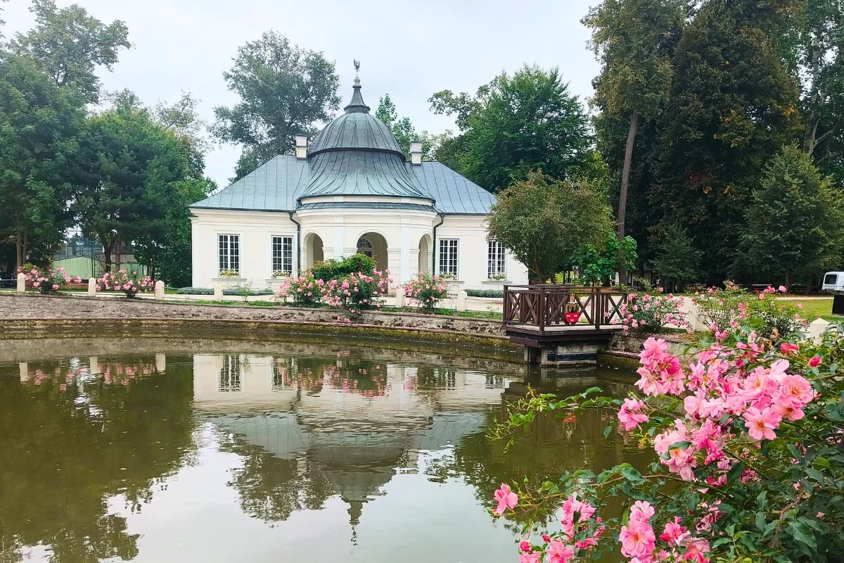 Spacer po pałacowych terenach to przyjemny sposób na spędzenie popołudnia Biały, klasycystyczny dworek otoczony ogrodem i stawem z ozdobnym mostkiem oraz kolorowymi kwiatami róż, położony wśród wysokich drzew.