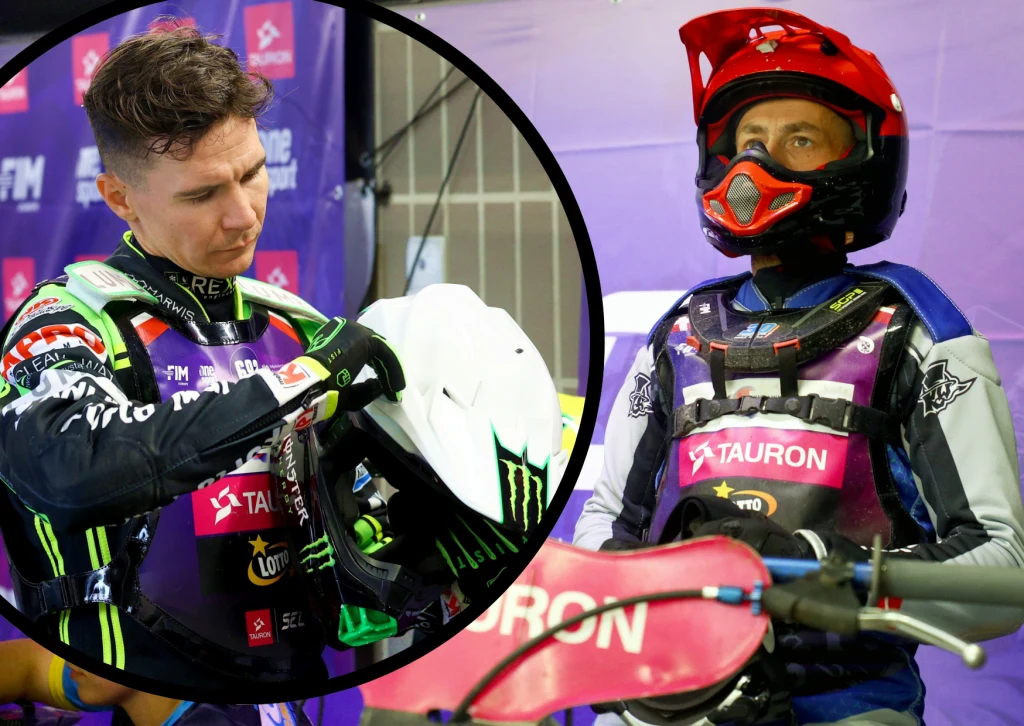 Dwóch żużlowców w strojach sportowych, jeden przygotowuje się do startu, zakładając kask, drugi siedzi na motocyklu gotowy do wyścigu, w tle widoczne logotypy sponsorów.