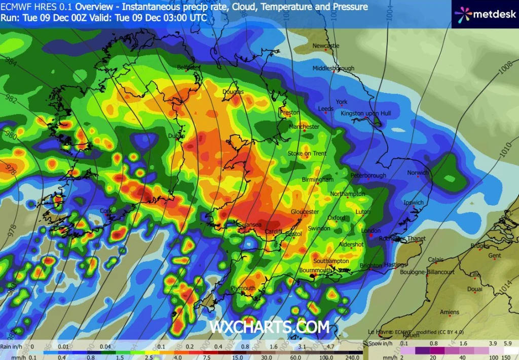 Mapa pogodowa Europy Zachodniej z intensywnymi opadami deszczu oznaczonymi kolorami od zielonego do czerwonego, obejmującymi m.in. Wielką Brytanię, Irlandię i okolice, z zaznaczonymi głównymi miastami i strefami największych opadów.