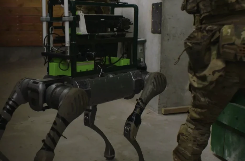 SBU stawia na technologie przyszłości, m.in. zdalnie sterowane robo-psy z karabinami Czteronożny robot wyposażony w urządzenia techniczne znajduje się obok osoby w mundurze wojskowym w pomieszczeniu o surowych ścianach.