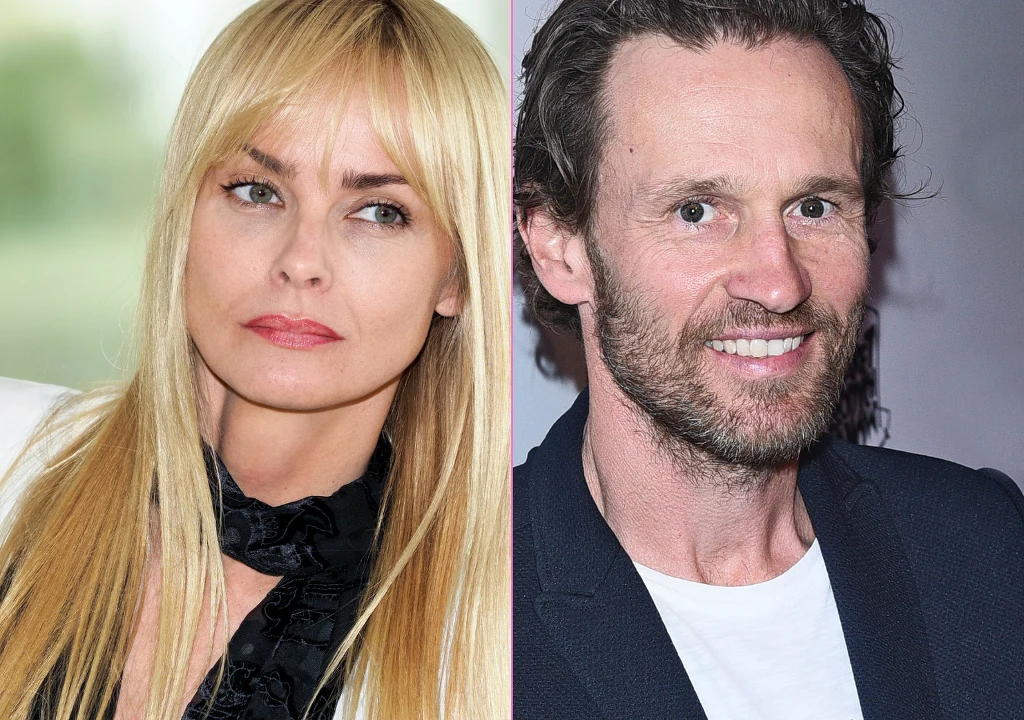 Dwie osoby przedstawione w formie portretu, po lewej stronie kobieta o blond włosach z poważnym wyrazem twarzy, po prawej stronie mężczyzna z brodą i szerokim uśmiechem. Tło jest rozmyte i neutralne, dzielone linią środkową.