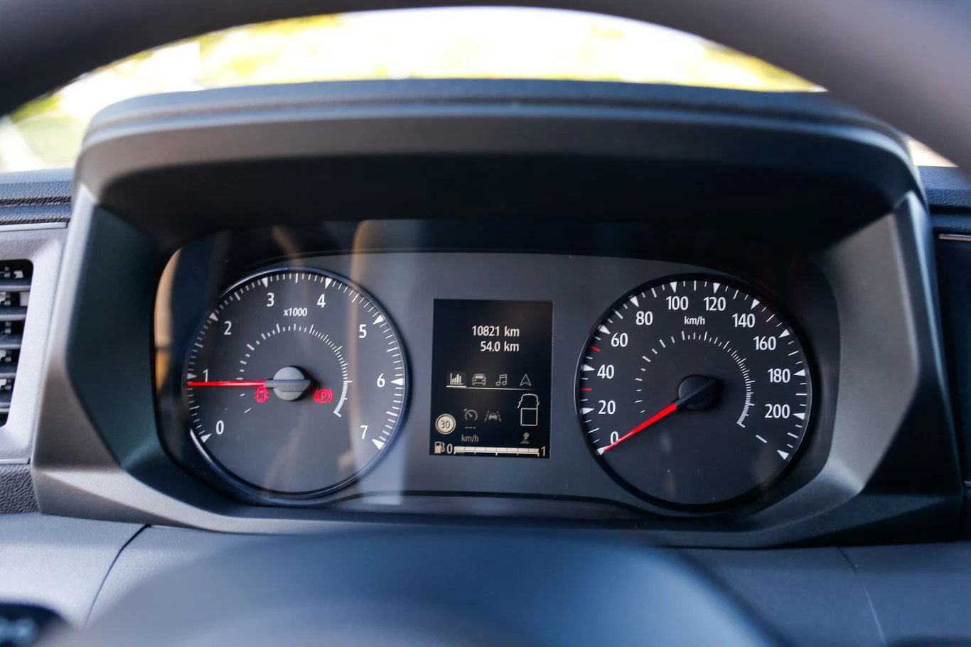 Kokpit samochodu z widocznymi zegarami prędkościomierza i obrotomierza, centralnym wyświetlaczem prezentującym przebieg pojazdu oraz wskaźnikiem poziomu paliwa.