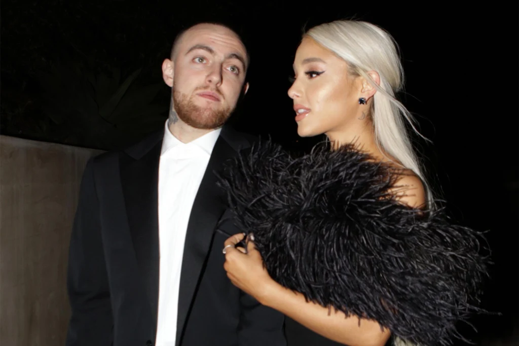 Ariana Grande i Mac Miller w 2018 r., niedługo przed rozstaniem Dwie elegancko ubrane osoby, mężczyzna w czarnym garniturze z białą koszulą oraz kobieta w czarnej kreacji z futrzanym szalem. Znajdują się na tle ciemnego nocnego otoczenia.