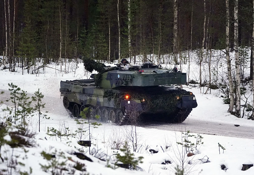 Sondaż. Finowie tracą zaufanie do Amerykanów, zapytano o pomoc USA w razie wojny Czołg wojskowy poruszający się po zaśnieżonej drodze leśnej, otoczony drzewami i krzakami, w zimowym krajobrazie.