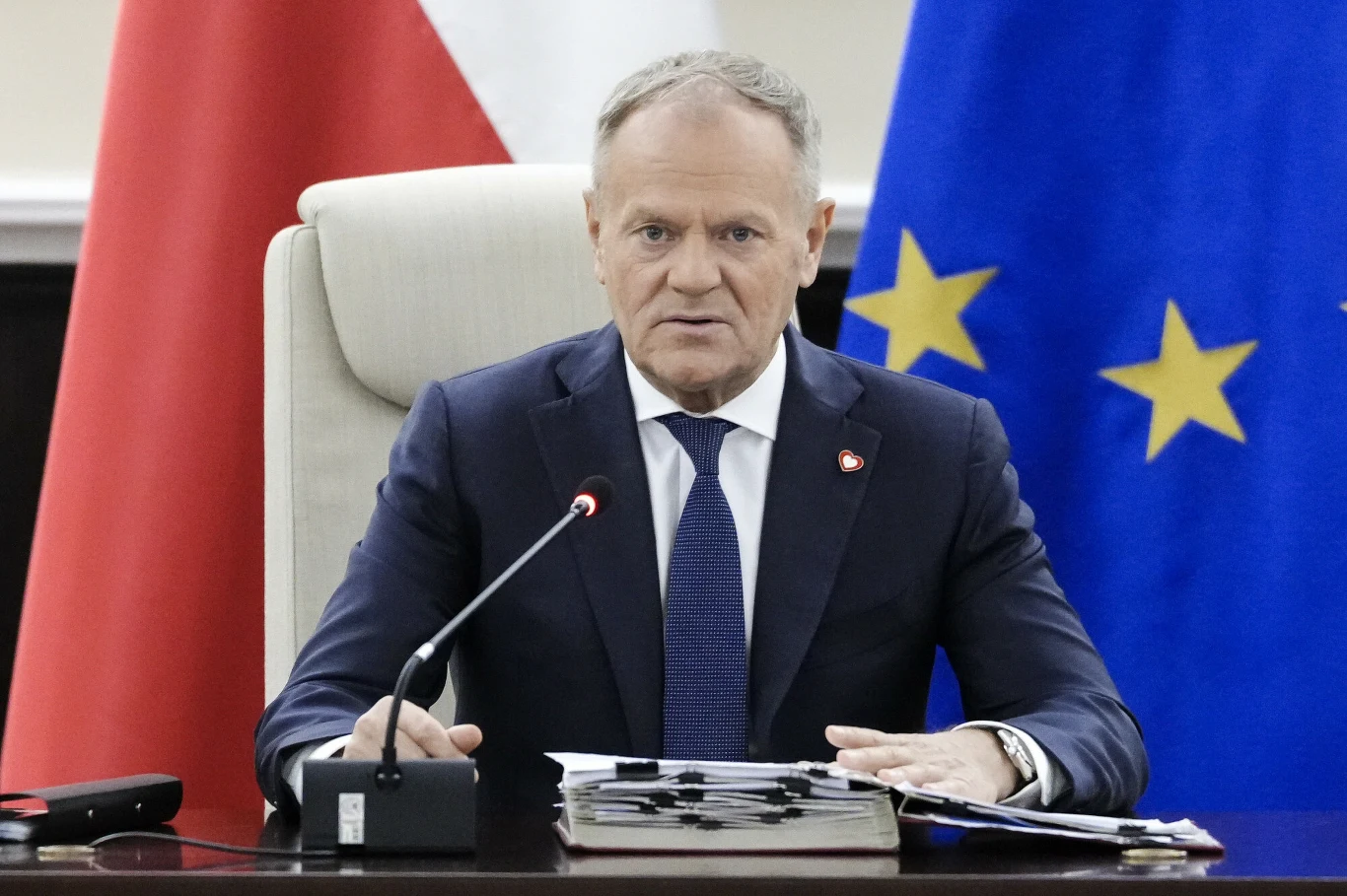 Jak Polacy oceniają prowadzenie polityki zagranicznej przez Donalda Tuska? Jest najnowszy sondaż Mężczyzna w garniturze siedzi przy stole konferencyjnym, przed nim mikrofon i dokumenty. W tle widoczne flagi Polski i Unii Europejskiej, co sugeruje oficjalny charakter spotkania.