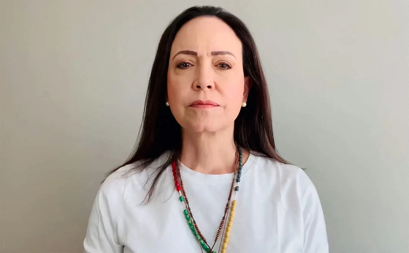 Wręczenie nagród Nobla. Laureatka Maria Corina Machado nie pojawi się na ceremonii, ale "jest bezpieczna" Kobieta o ciemnych włosach w białej bluzce patrzy prosto w obiektyw. Na szyi ma kilka kolorowych korali. Tło jednolite w jasnym odcieniu szarości.