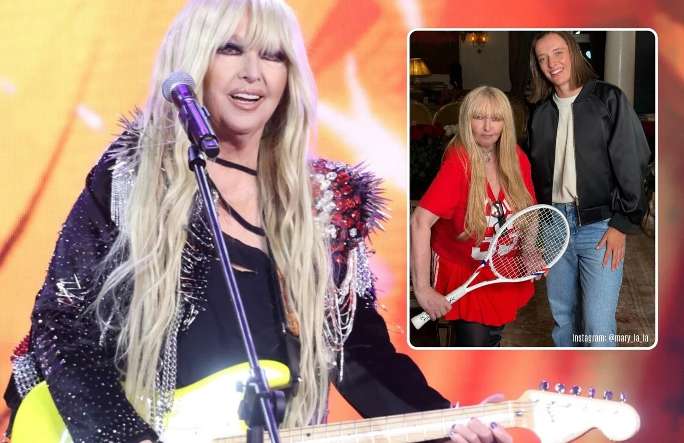 Kobieta z długimi blond włosami występuje na scenie z gitarą elektryczną w ręku, ubrana w czarną kreację z cekinami oraz ozdobną kurtkę. W prawym górnym rogu widoczna jest wstawka przedstawiająca tę samą kobietę w czerwonej koszulce i z rakietą tenisow...