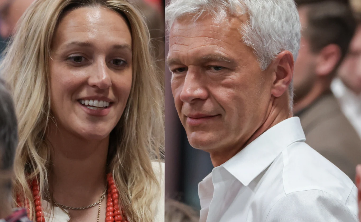 Dwie osoby, kobieta o blond włosach z naszyjnikiem z czerwonych korali oraz mężczyzna o siwych włosach w białej koszuli, ujęte w tłumie.