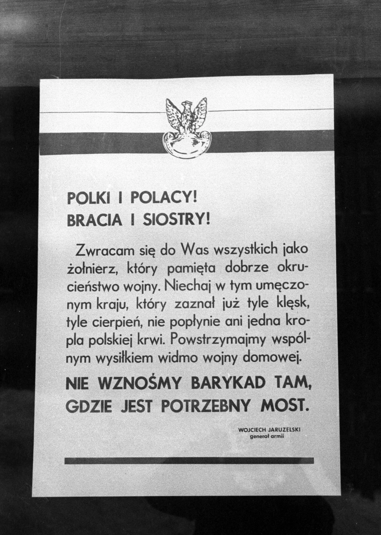 Afisz a apelem gen. Wojciecha Jaruzelskiego; 18 grudnia 1981 r. Plakat z apelem do Polaków o powstrzymanie się od przemocy i unikanie wznoszenia barykad w miejscach, gdzie potrzebna jest jedność, z wyraźnym hasłem w dolnej części oraz godłem Polski na górze.