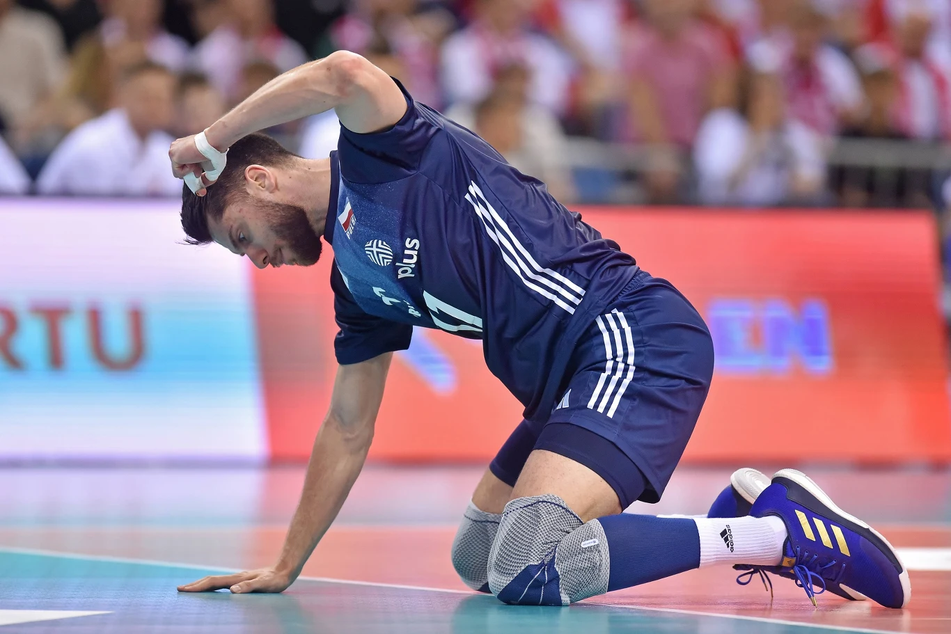 Aleksander Śliwka wciąż nie jest w stanie grać w pełnym wymiarze Siatkarz w granatowym stroju klęczy na boisku, opierając się jedną ręką o podłoże i drugą trzymając się za głowę, w tle rozmyta publiczność na trybunach.