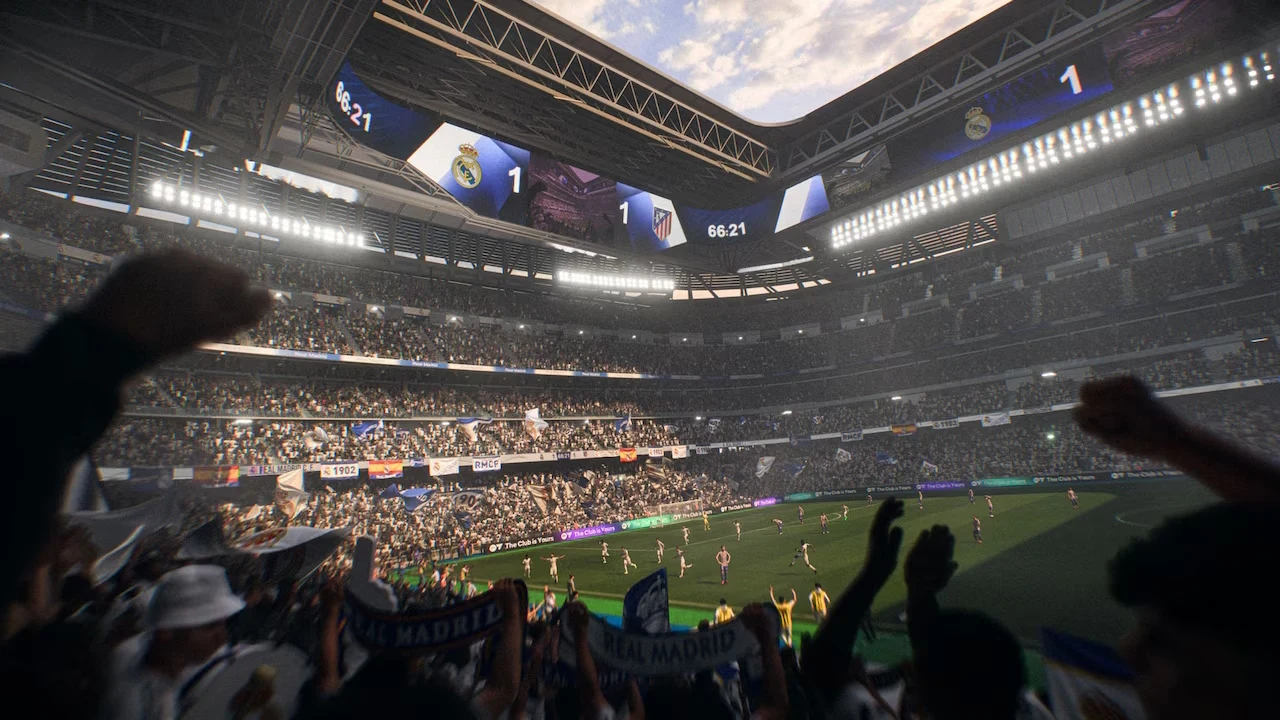 EA Sports FC 26 Tłum kibiców na dużym, nowoczesnym stadionie piłkarskim, z zadaszeniem otwartym nad boiskiem, dopingujący zawodników podczas meczu; na elektronicznej tablicy wyników widać remis 1:1, a atmosfera wydarzenia jest pełna emocji.