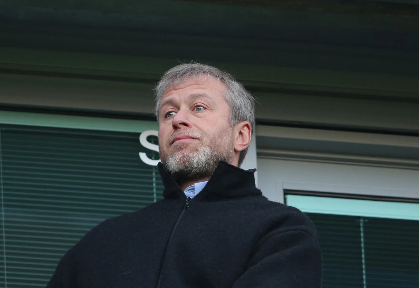 Rosyjscy oligarchowie, w tym Roman Abramowicz (na zdj.), domagają się od europejskich krajów 56 mld euro odszkodowań za nałożone na nich sankcje Mężczyzna z siwą brodą ubrany w ciemną kurtkę stoi przed przeszkleniem z poziomymi żaluzjami, patrząc przed siebie z poważnym wyrazem twarzy.