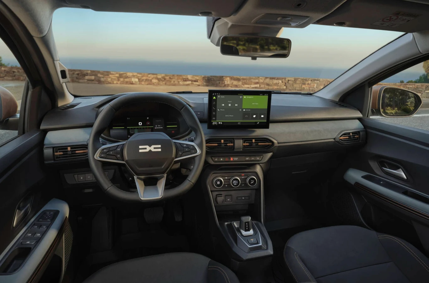 Konsola ma bardziej logiczny układ, a tworzywa są trwalsze i łatwiejsze w czyszczeniu. Nowoczesna deska rozdzielcza samochodu z cyfrowym panelem, ekranem nawigacyjnym i wielofunkcyjną kierownicą, eleganckie, minimalistyczne wnętrze utrzymane w ciemnej kolorystyce, widok na zewnątrz przez panoramiczną szybę.